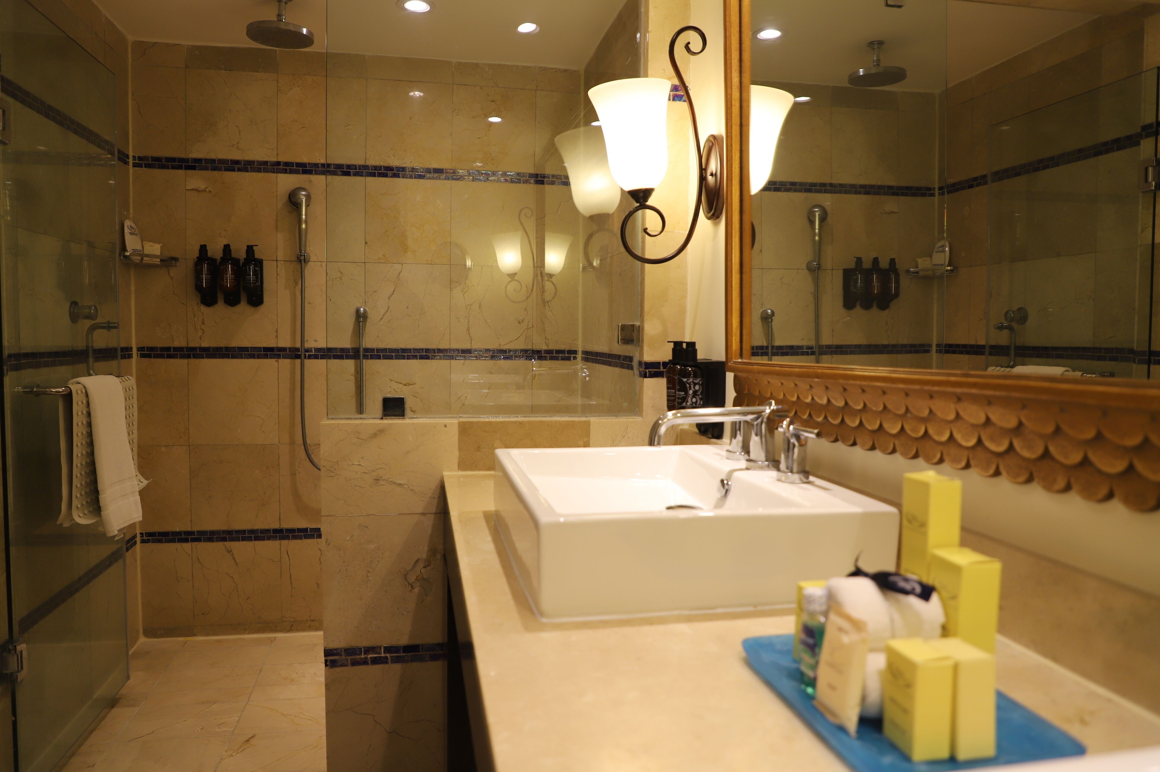 A modern bathroom with a large mirror, a white sink, and a shower area.