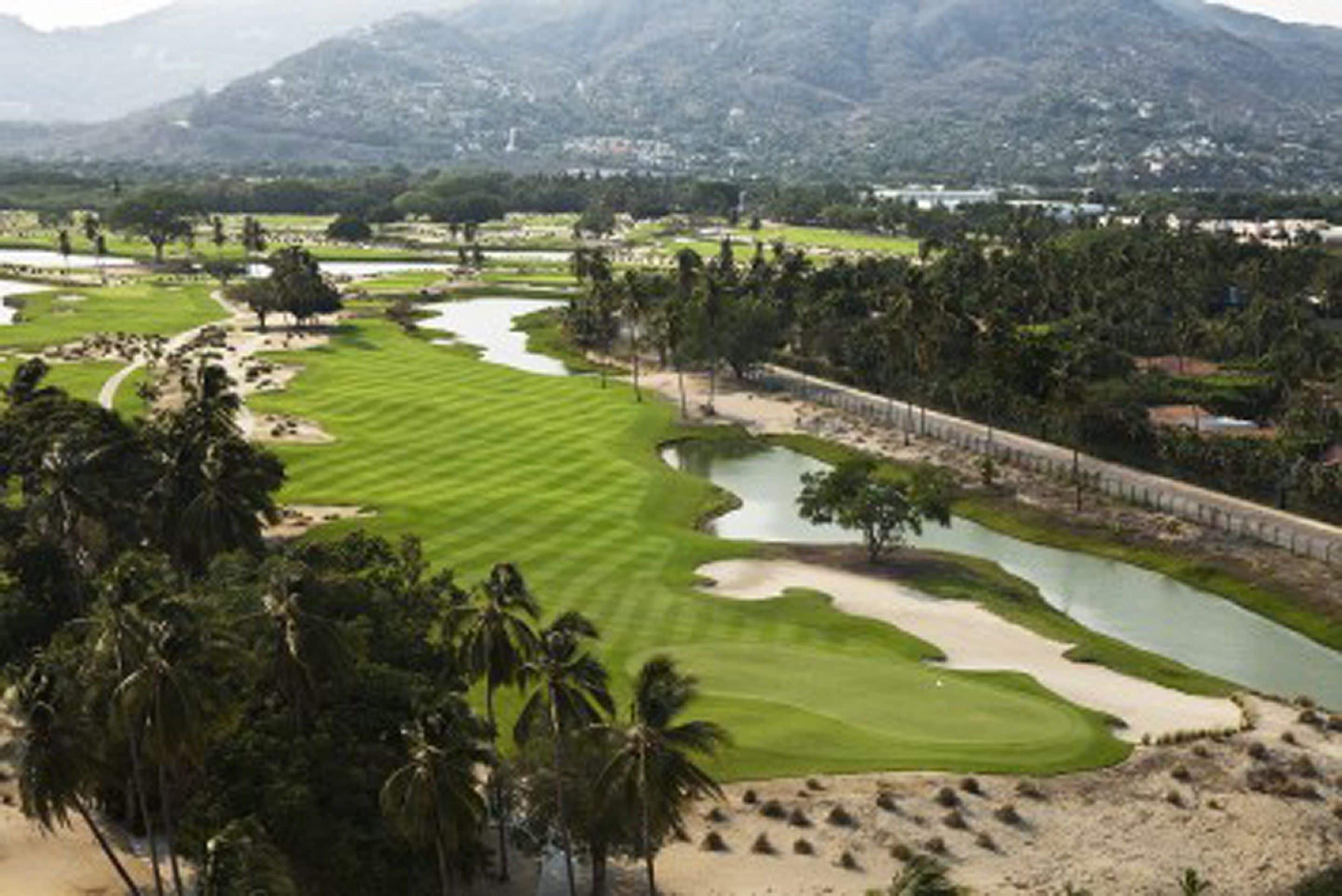 A golf course with sand bunkers, water hazards, and palm trees.