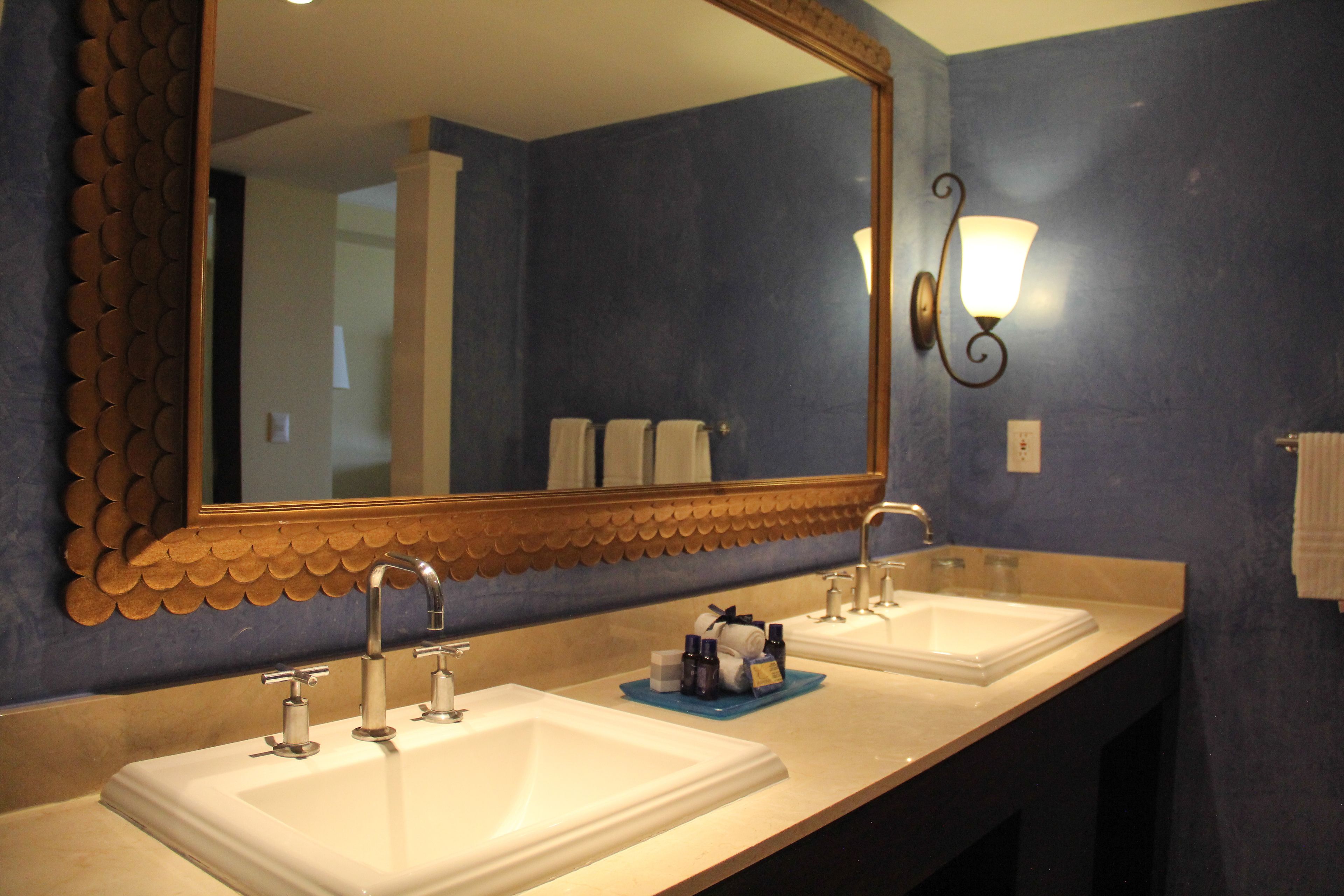 A bathroom with two sinks, a large mirror, and a wall-mounted light fixture.
