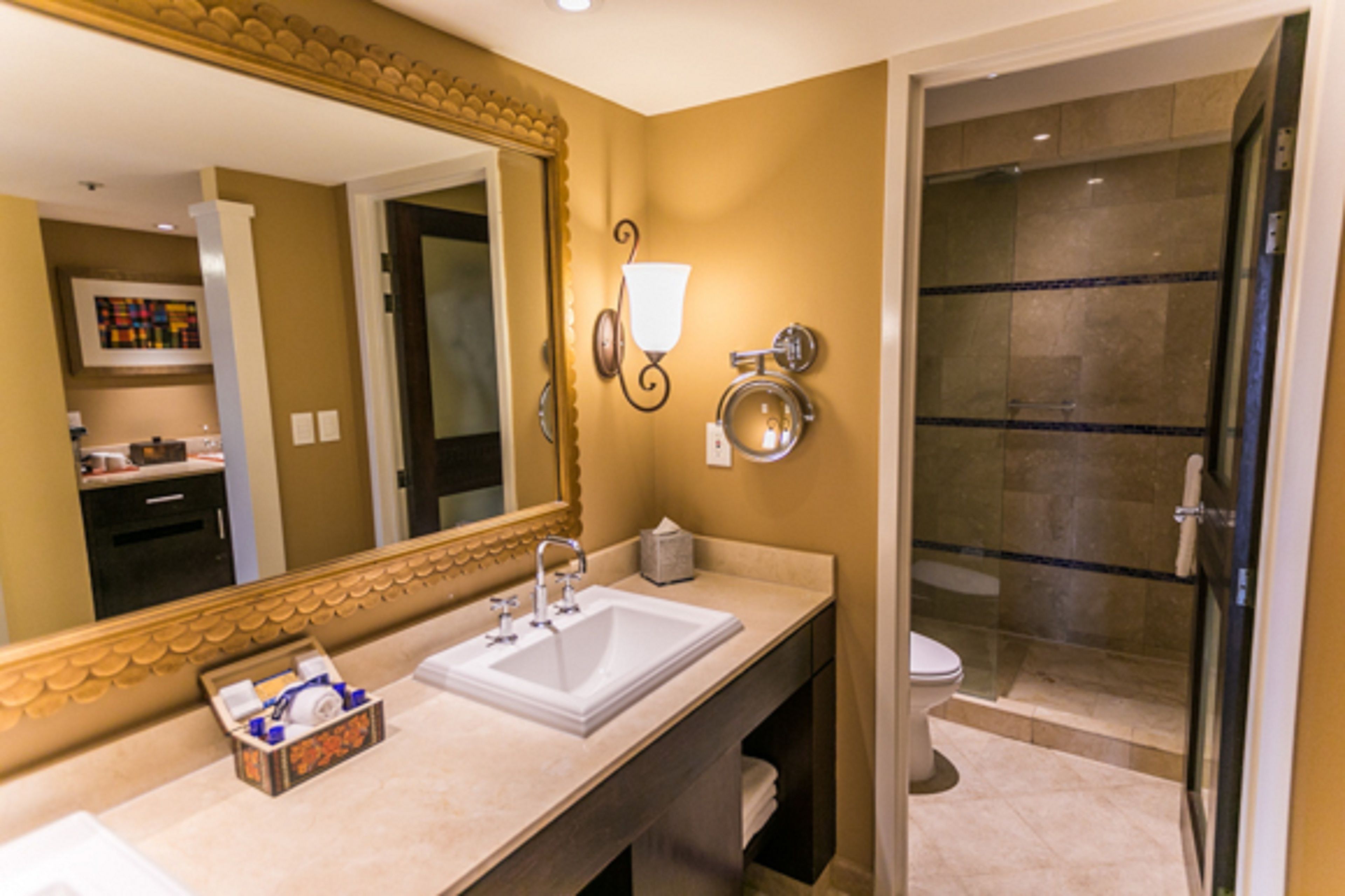 A bathroom with a large mirror, a sink, a toilet, and a glass-enclosed shower.