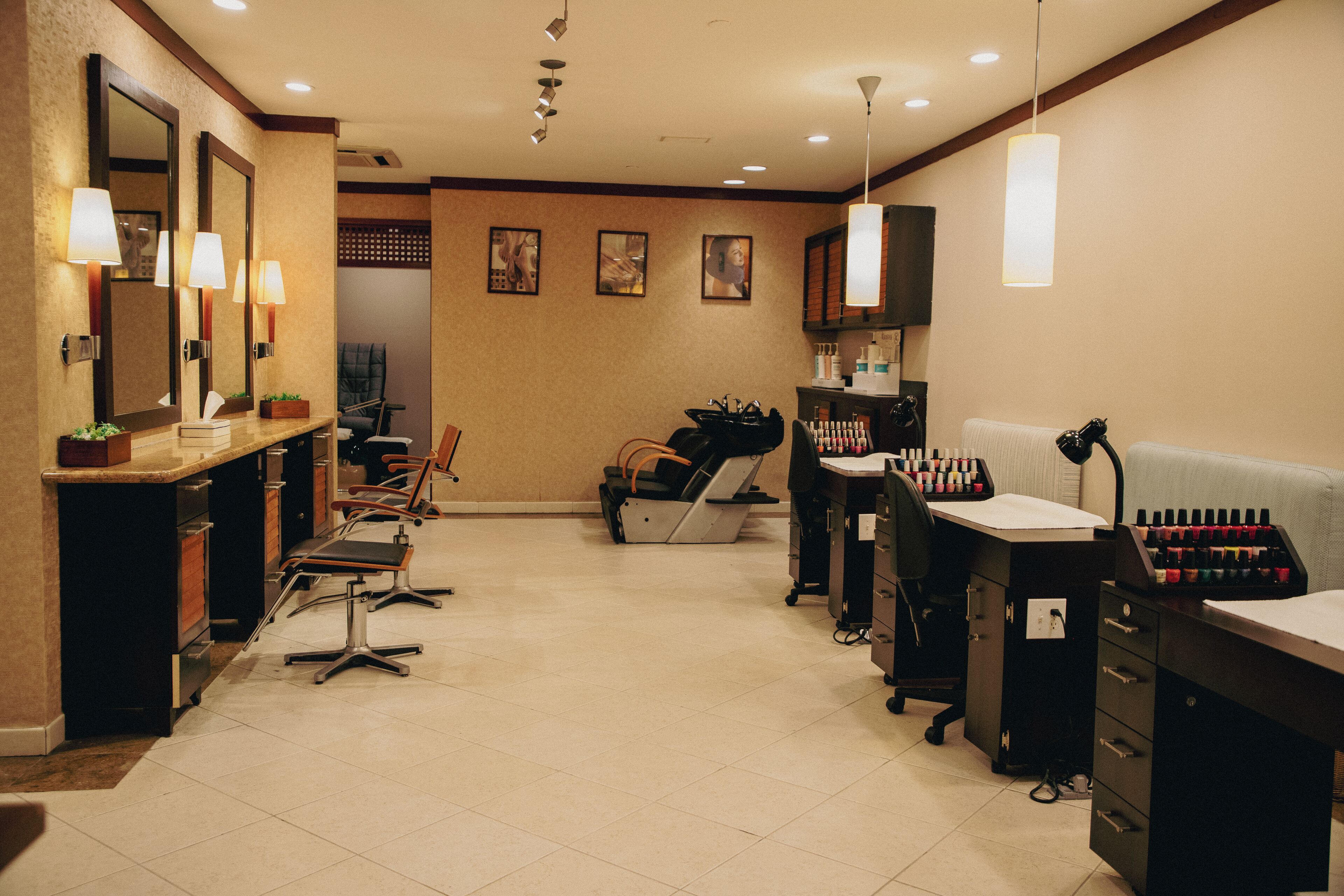 Un salón con múltiples sillas, una barra con espejo y diversos productos para el cabello.