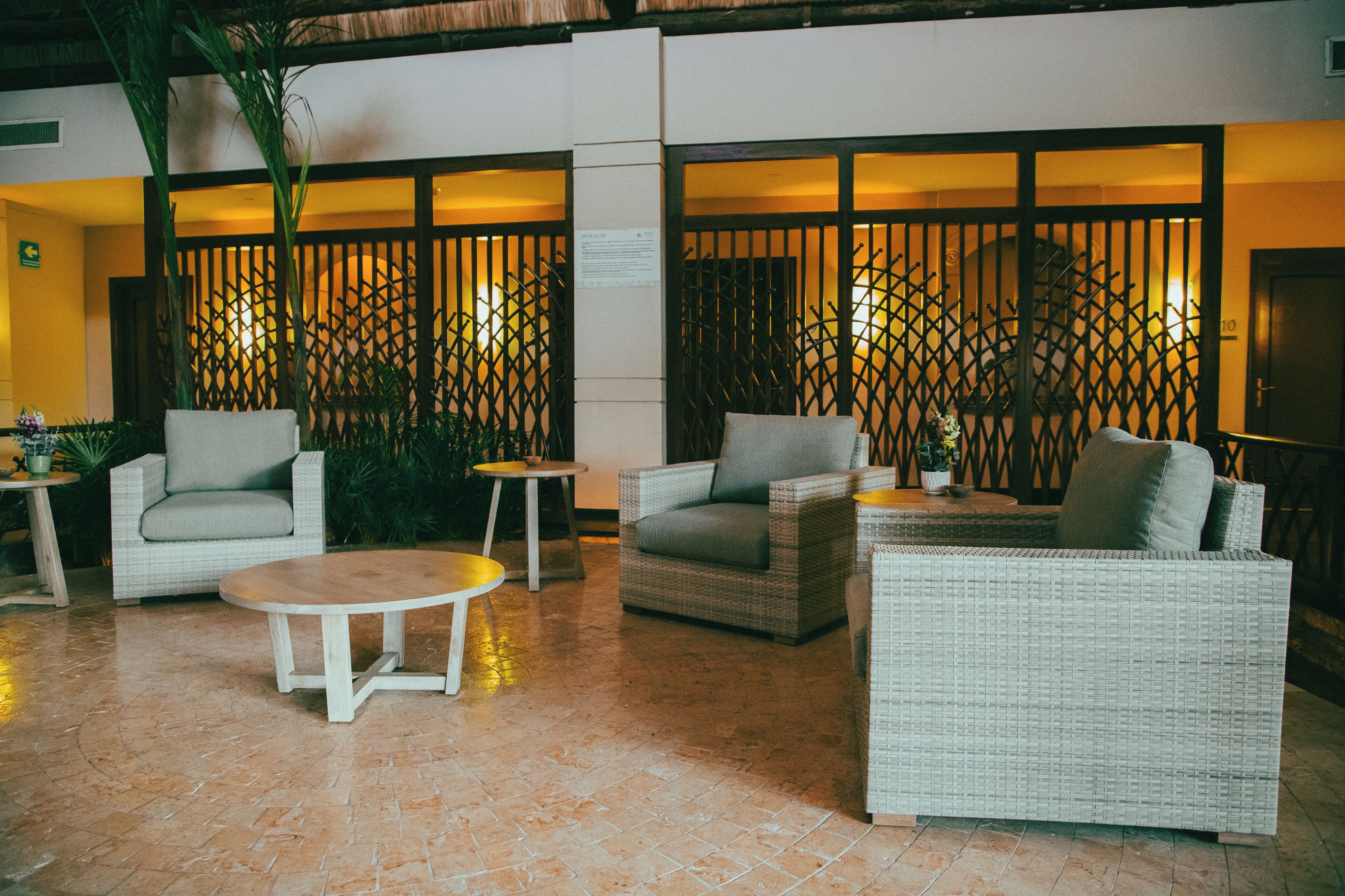 Un vestíbulo con muebles de mimbre, una mesa redonda y una valla decorativa.