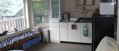 A compact kitchen with a refrigerator, stove, and a window with a view of the outside.