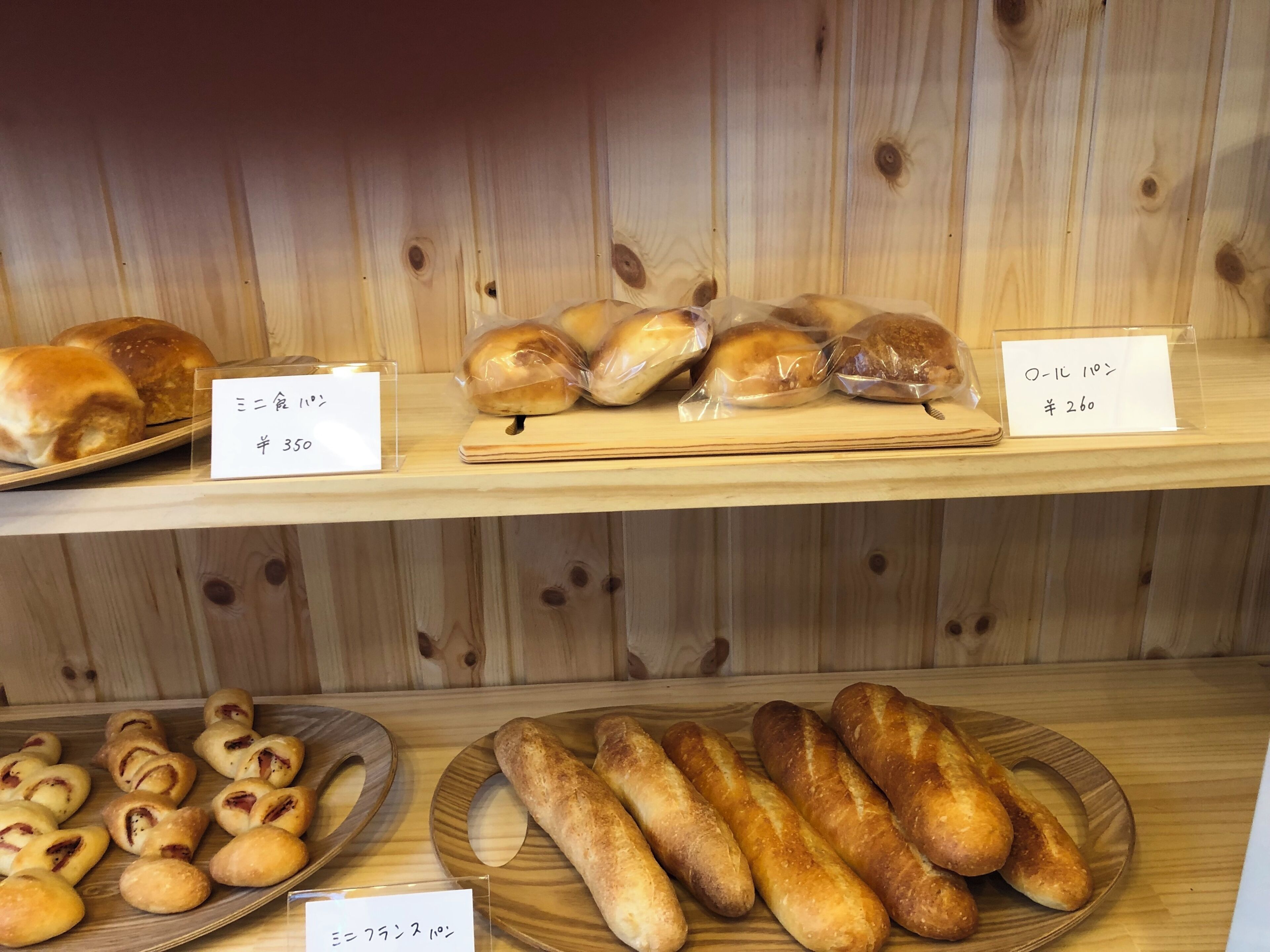 A bakery display with various baked goods, including bread and rolls, with price tags.