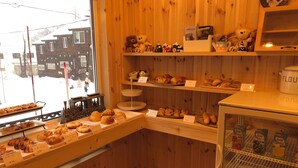 A bakery with wooden interior, various baked goods displayed, and a refrigerator with dairy products. - Pension Locomotion (Kutchan)