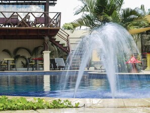 Relax by the serene pool, surrounded by lush greenery and a central water feature.
