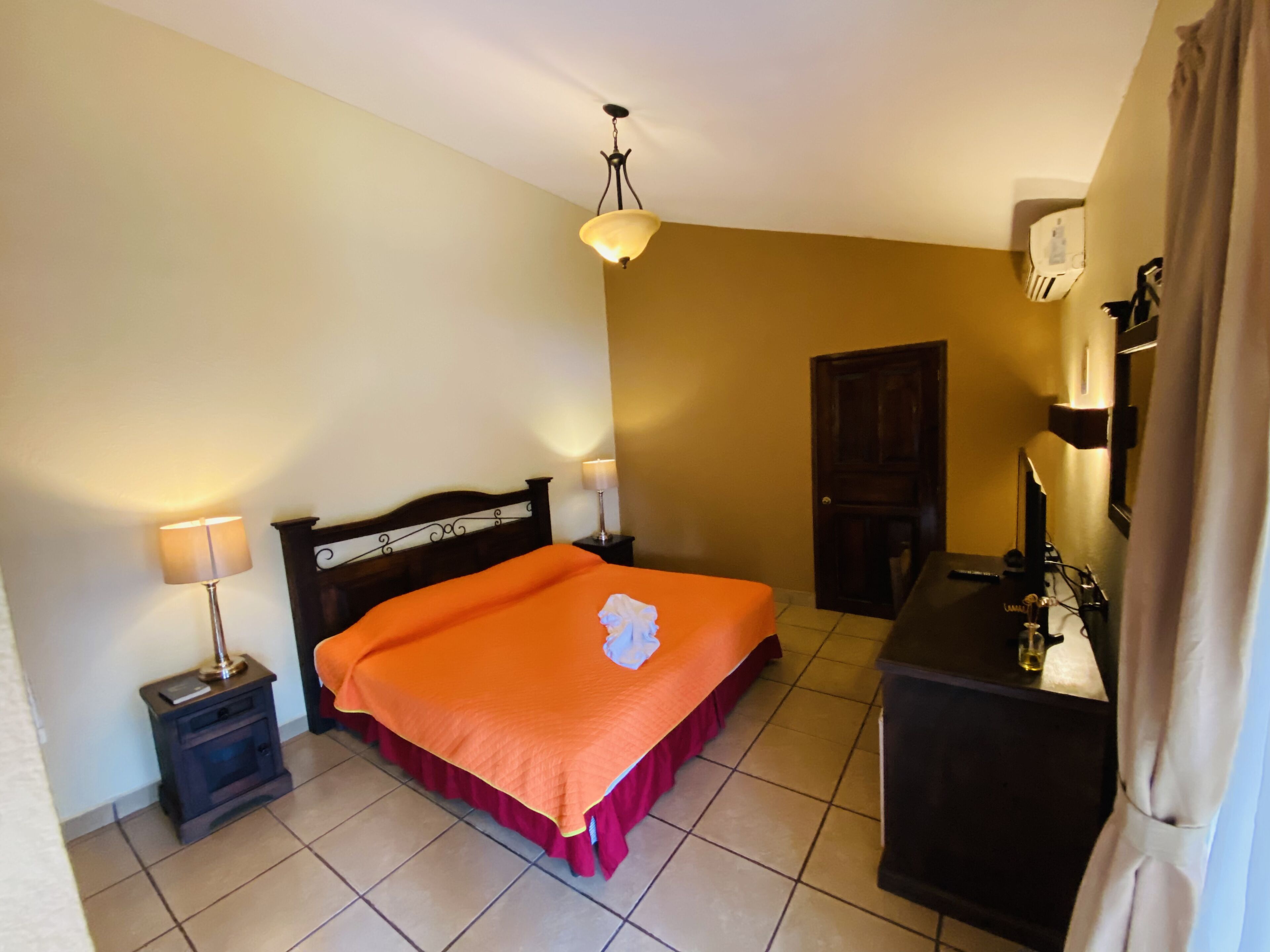 Un dormitorio con cama, mesita de noche, cómoda y puerta.