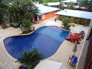 Relax by the oval-shaped pool surrounded by palm trees and lounge chairs.