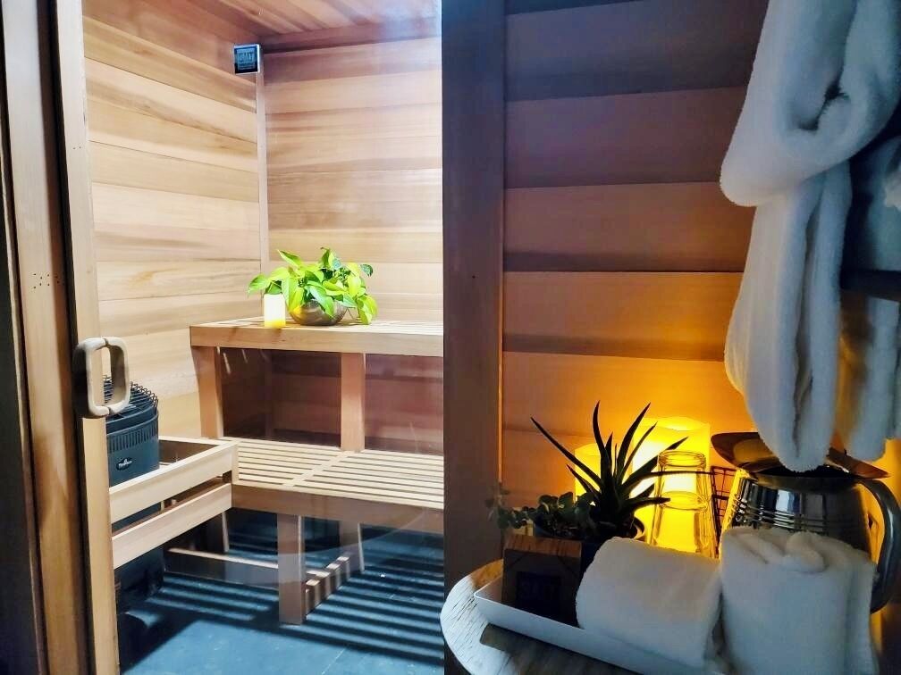A sauna room with wooden walls, a bench, a small table with a plant, and towels.
