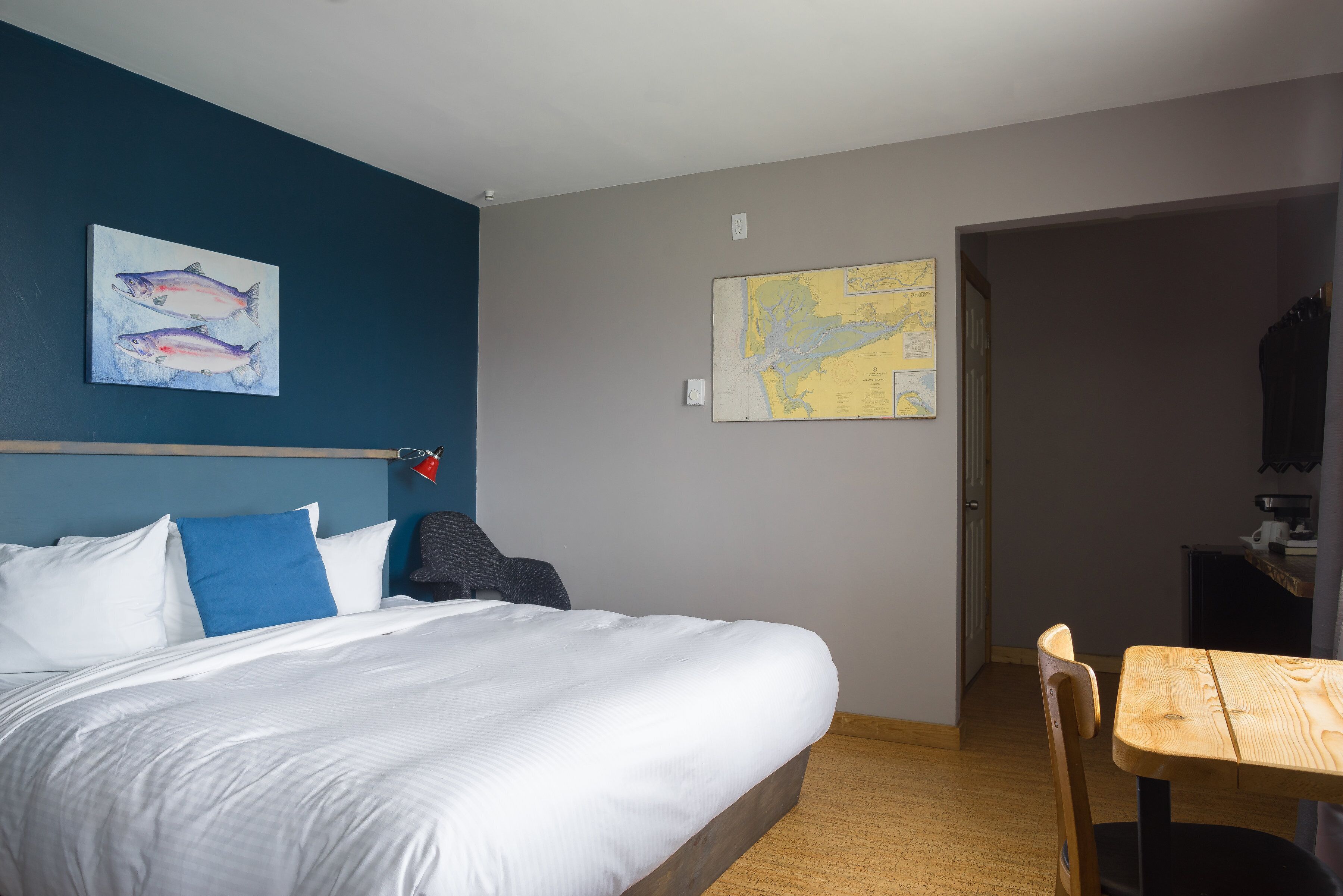 Una habitació d'hotel amb un llit, una taula de treball i un mapa a la paret.