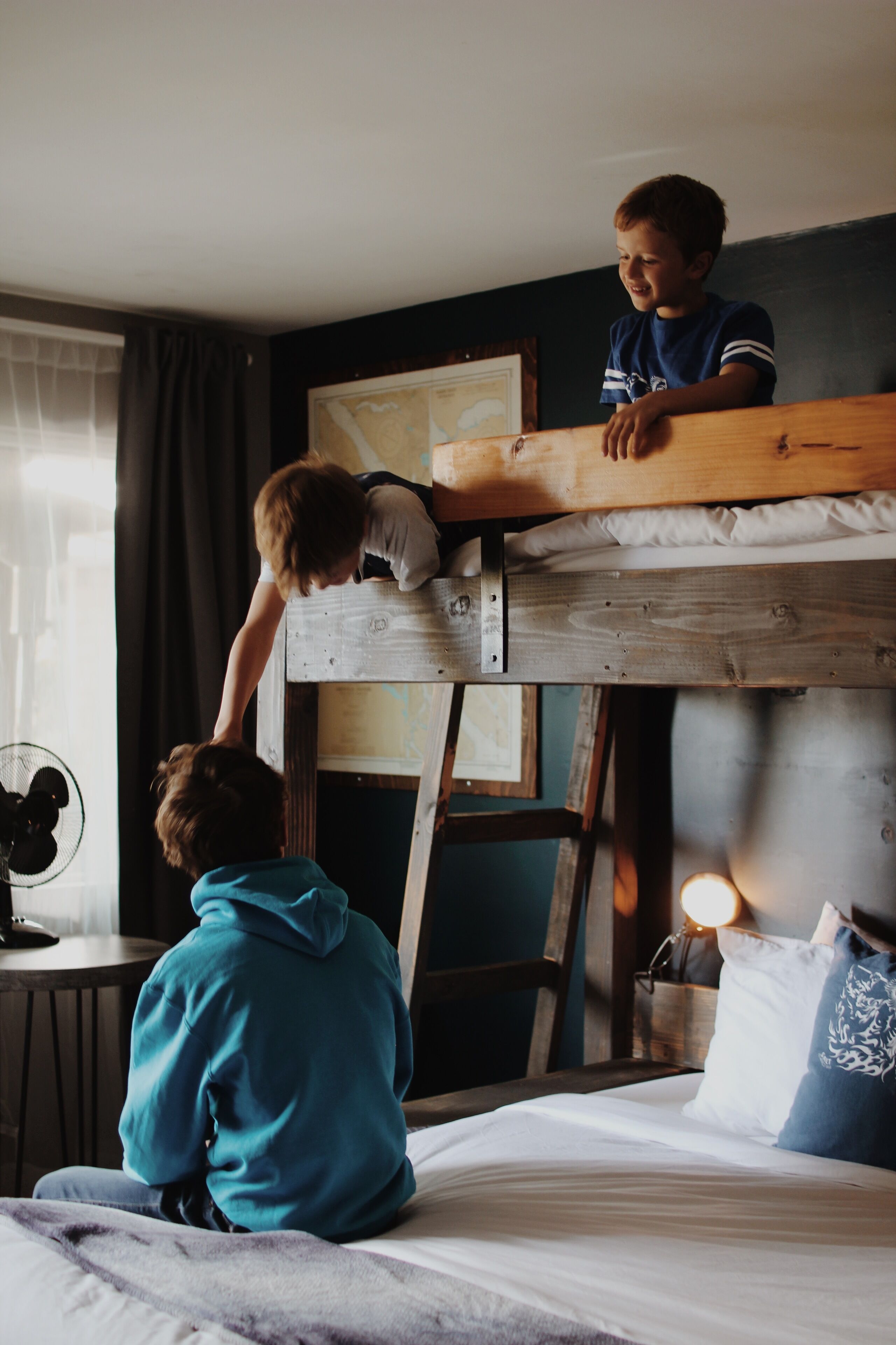 A bunk bed with two children, one sitting and one standing.