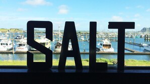 Large letters spelling "SALT" in front of a marina with boats. - Salt Hotel & Pub (Ilwaco)