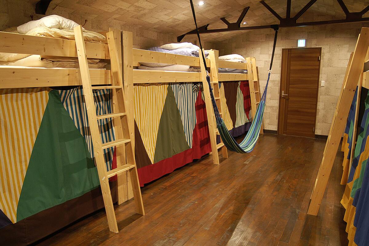 Ein Zimmer mit Stockbetten, Hängematten und einer Holztür.
