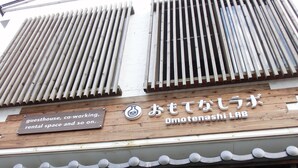 A building with a sign indicating it is a guesthouse, co-working space, and rental space. - Omotenashi LAB - Hostel (Sakura)