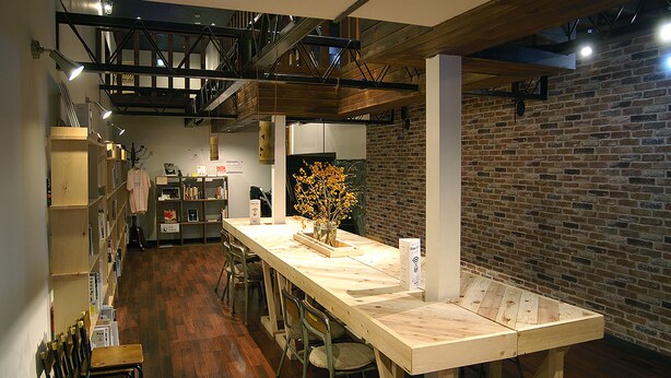 A spacious kitchen with a long wooden table, brick walls, and exposed beams. - Omotenashi LAB - Hostel (Sakura)