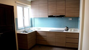 A kitchen with wooden cabinets, a sink, and a window. - Riverside Residence by Gina Suite (Bandar Seri Begawan)