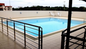 A swimming pool with a tiled deck and a covered seating area with chairs. - Riverside Residence by Gina Suite (Bandar Seri Begawan)