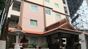 A multi-story hotel with a central courtyard, balconies, and a large glass structure in the background. - Kim Hostel at Morleng (Bangkok)