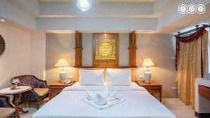 A hotel room with a large bed, two bedside tables, a nightstand, a chair, and a decorative wall panel. - Kim Hostel at Morleng (Bangkok)