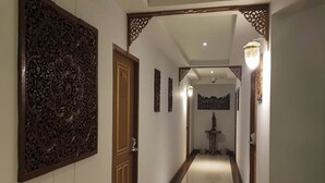 A hallway with a wooden door, a wall-mounted decorative panel, and a light fixture. - Kim Hostel at Morleng (Bangkok)