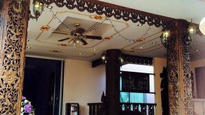A traditional building with ornate wooden pillars, a ceiling fan, and a tiled floor. - Kim Hostel at Morleng (Bangkok)