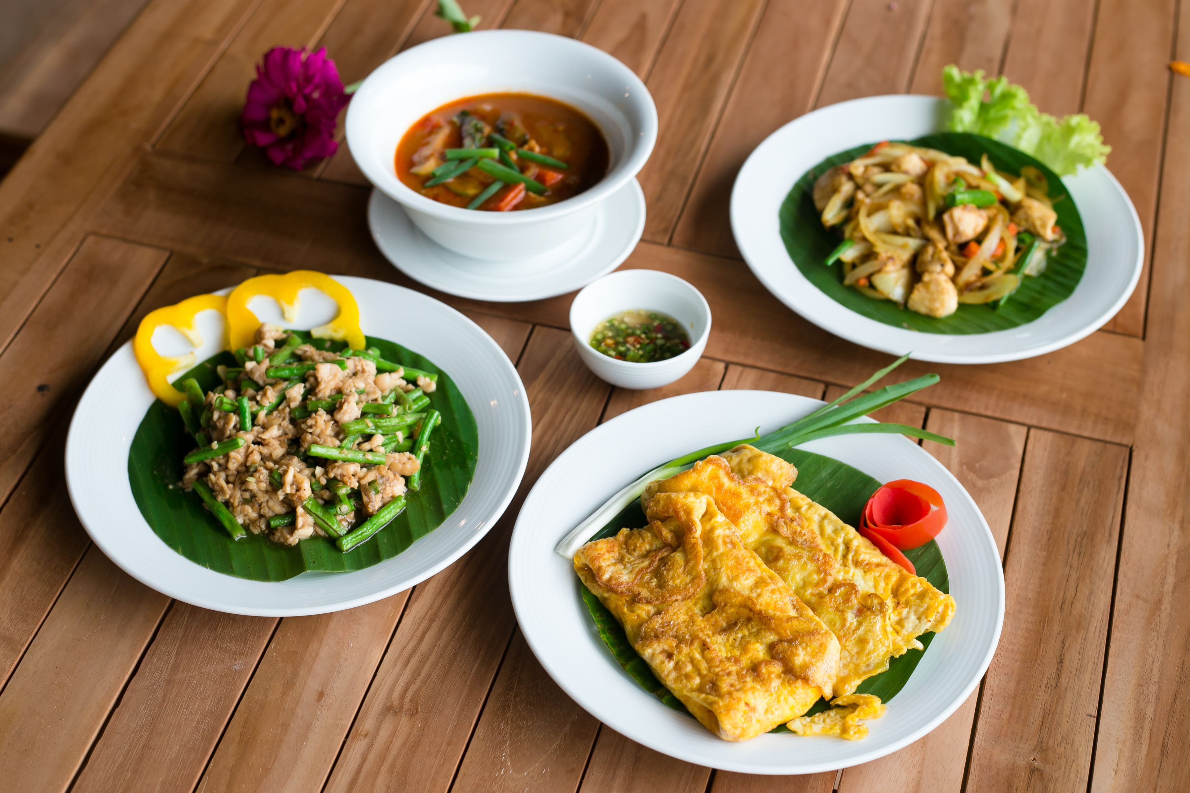 A wooden table with three plates of food, each with different dishes.