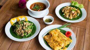 A wooden table with three plates of food, each with different dishes.