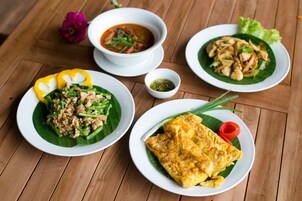 A wooden table with three plates of food, each with different dishes.