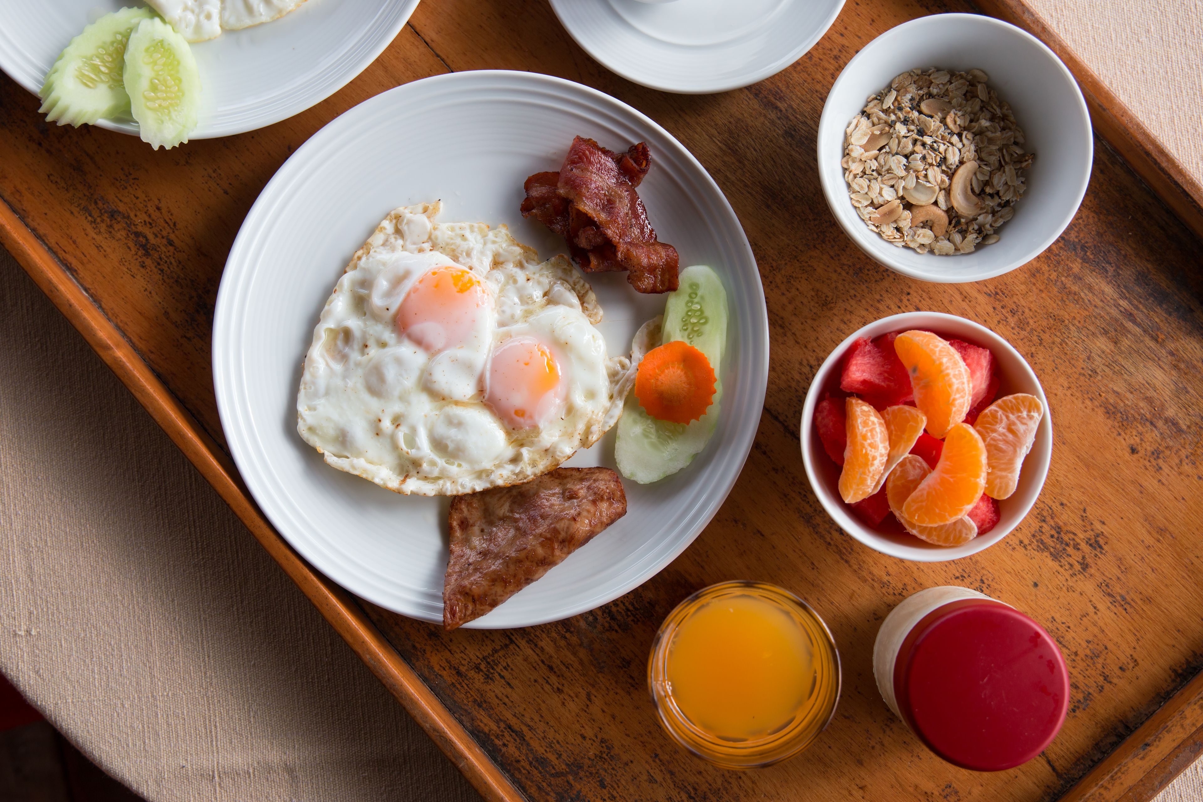 Bandeja de desayuno con huevos, tocino, salchicha, verduras y fruta.
