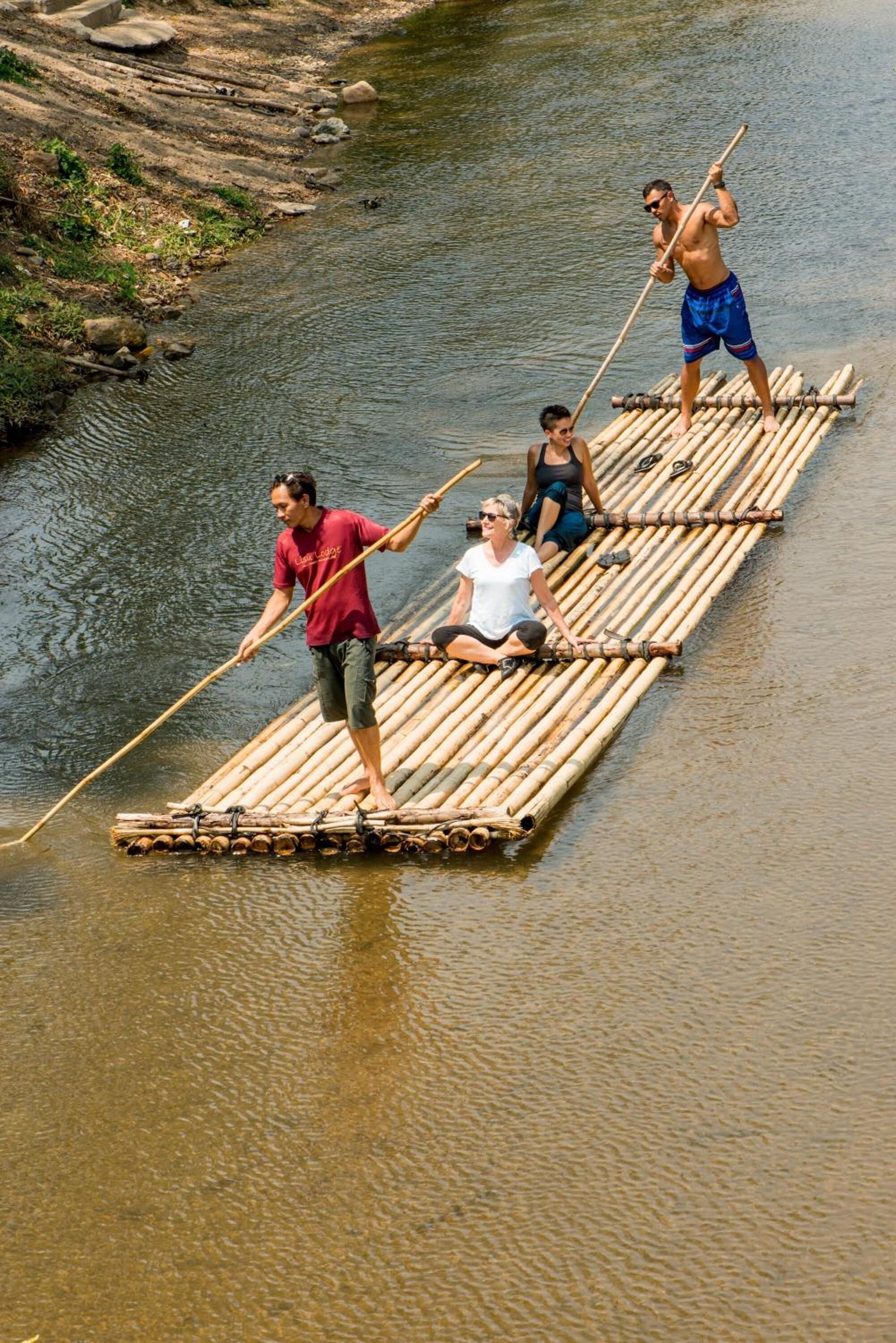 People on a bamboo raft in a river.