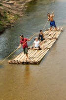 People on a bamboo raft in a river.