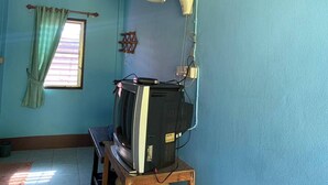 A room with a television on a wooden stand, a ceiling fan, a window with curtains, and a wall-mounted electrical outlet. - Ruenview Resort (Mae Chan)