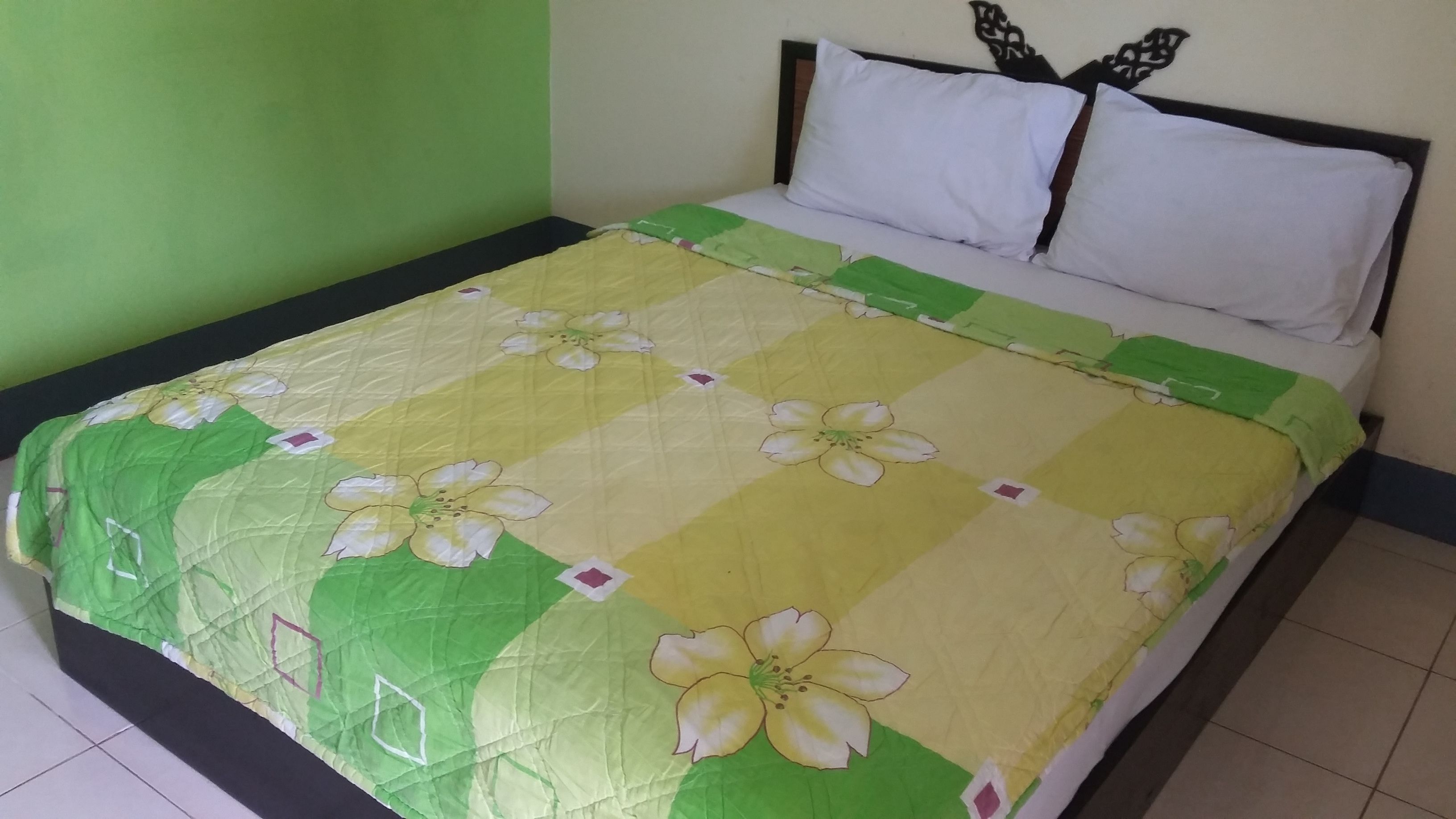 A bed with a floral bedspread, white pillows, and a headboard with a decorative design.