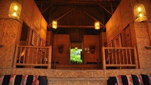 A rustic wooden building with a covered entrance, wooden railings, and hanging light fixtures.