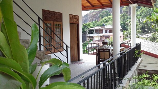 A covered outdoor area with a staircase leading to a wooden door, surrounded by greenery. - Srimali's Residence (Unawatuna)