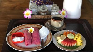 A tray with a plate of pink crepes, a cup of coffee, and a plate of fruit. - Depa House (Ubud)