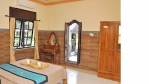 A bedroom with a bed, a wooden dresser, a mirror, and a window with curtains. - Depa House (Ubud)