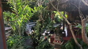 A lush indoor garden with various plants and a statue. - Depa House (Ubud)