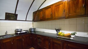 A kitchen with wooden cabinets, a black countertop, and a tiled backsplash. - Marvel Cruise (Kuttanad Taluk)
