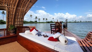 A boat deck with a wooden bench, cushions, a steering wheel, and a potted plant. - Marvel Cruise (Kuttanad Taluk)