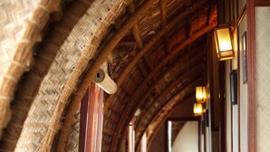 A corridor with wooden benches, a thatched ceiling, and traditional lanterns. - Marvel Cruise (Kuttanad Taluk)