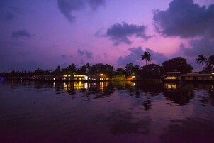 A waterfront hotel with a reflection of palm trees and buildings in the water.