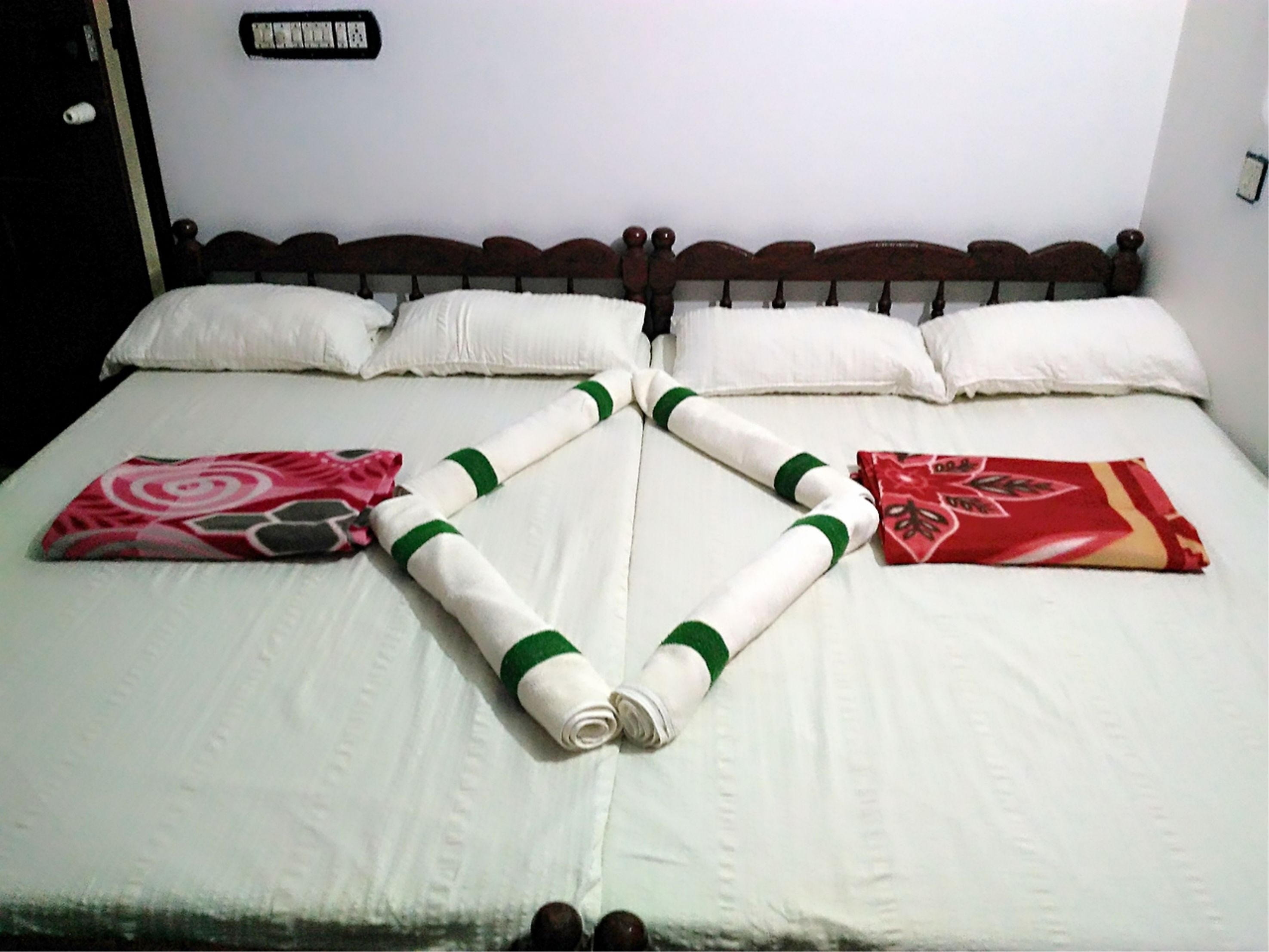 Ein ordentlich bezogenes Bett mit weißer Bettwäsche und Kissen, ein Holzkopfteil und ein Schild an der Wand.