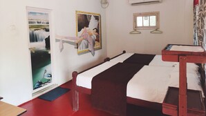 Ein Zimmer mit zwei Betten, einem Deckenventilator, einer Klimaanlage, einem Fenster und einer Tür mit Blick auf einen Wasserfall.