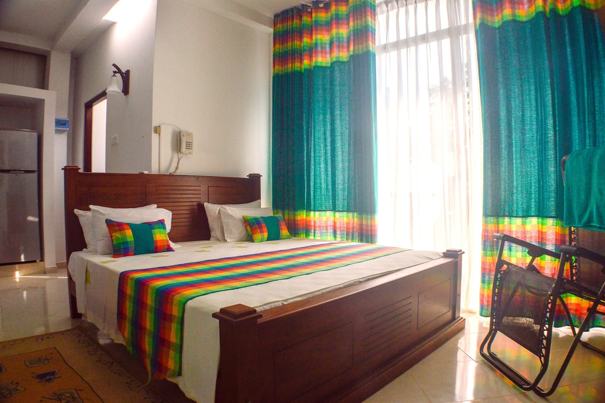 Una habitación de hotel con una cama, una silla, un refrigerador y cortinas.