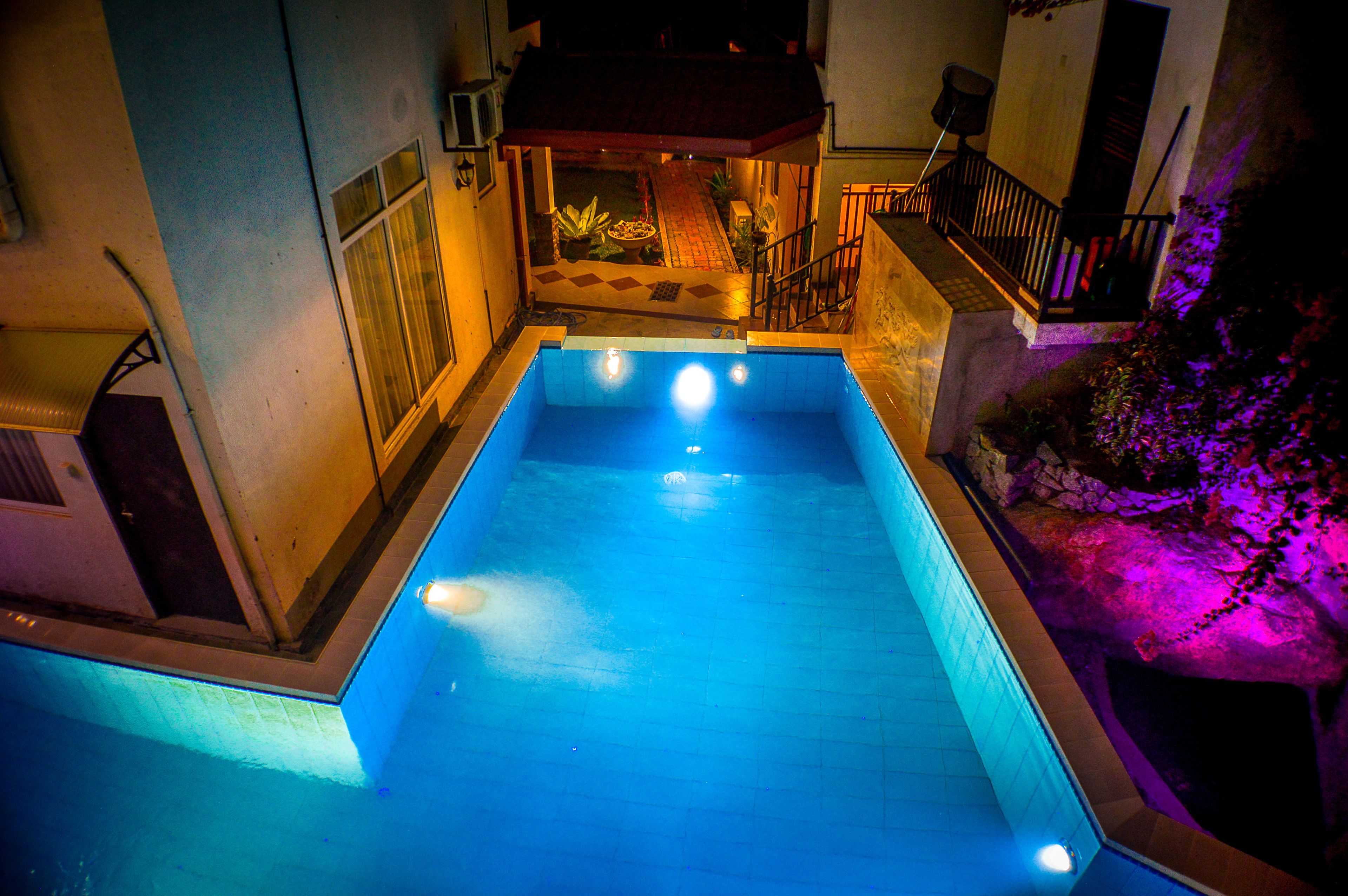 A rectangular swimming pool with a tiled edge and a small deck area in the background.