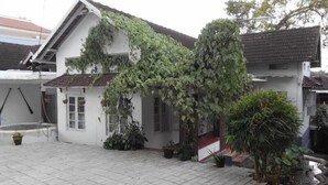 Ein weißes Gebäude mit Ziegeldach und einem Gartenbereich mit Topfpflanzen.