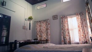 Ein Schlafzimmer mit Bett, Schreibtisch und einem Fenster mit Vorhängen.