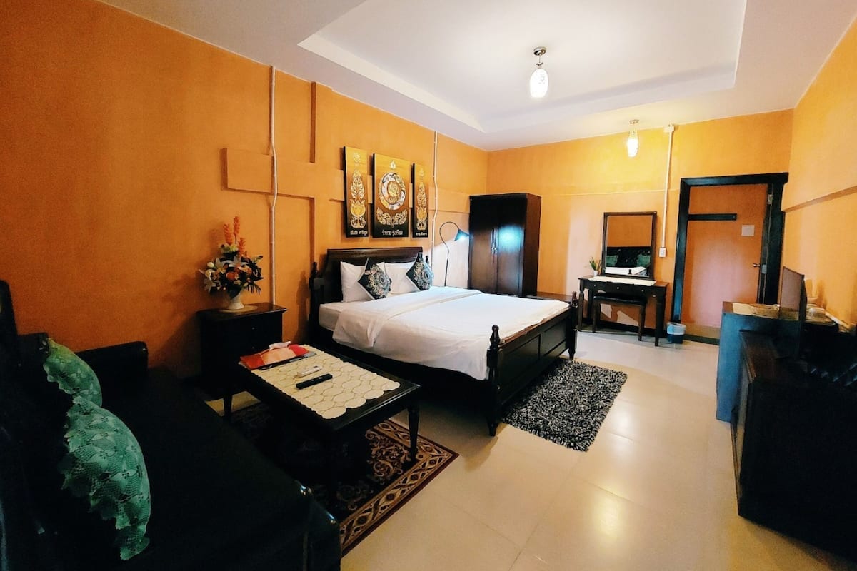 Una habitación de hotel con una cama, un escritorio, una silla, un armario y un espejo.