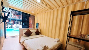 Een hotelkamer met een bed, een spiegel en uitzicht op het zwembad.